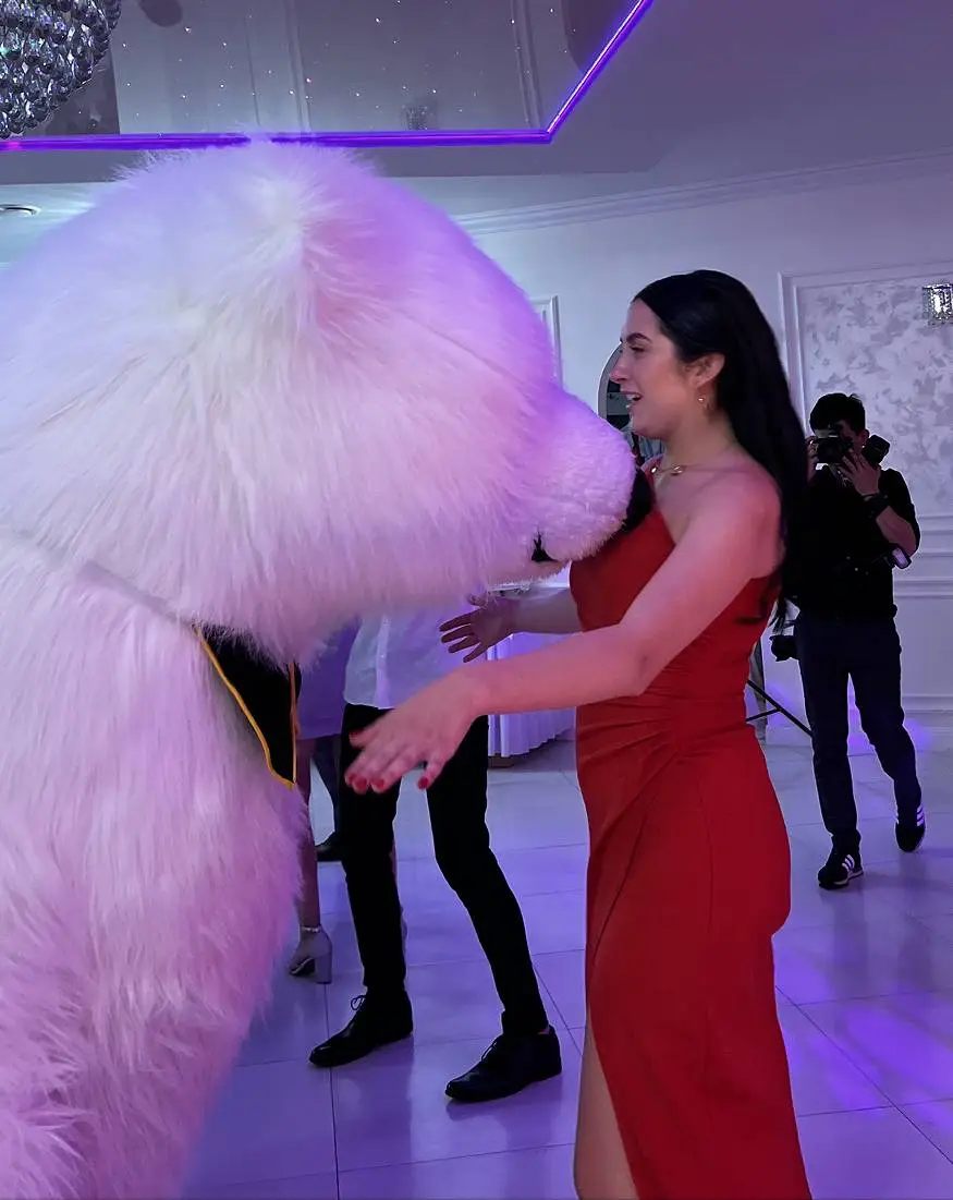 Woman in red dress hugging a polar bear mascot during a party event in Vancouver