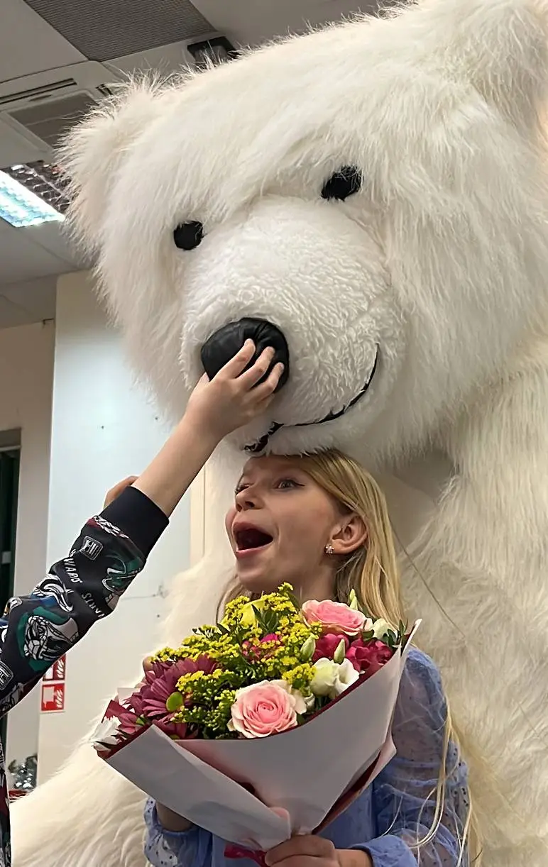 Girl holding a flower bouquet with a polar bear mascot at a kids party in Vancouver