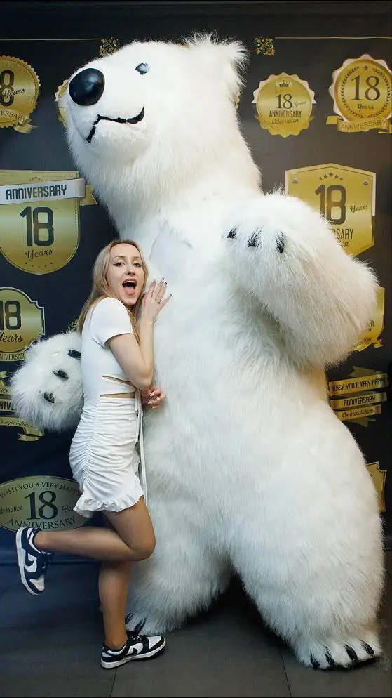 Woman posing with a life-size polar bear mascot at a party event in Vancouver